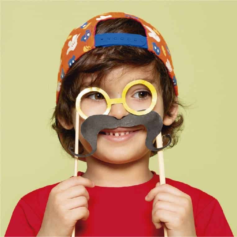 Niño con máscara y bigote falsos de papel